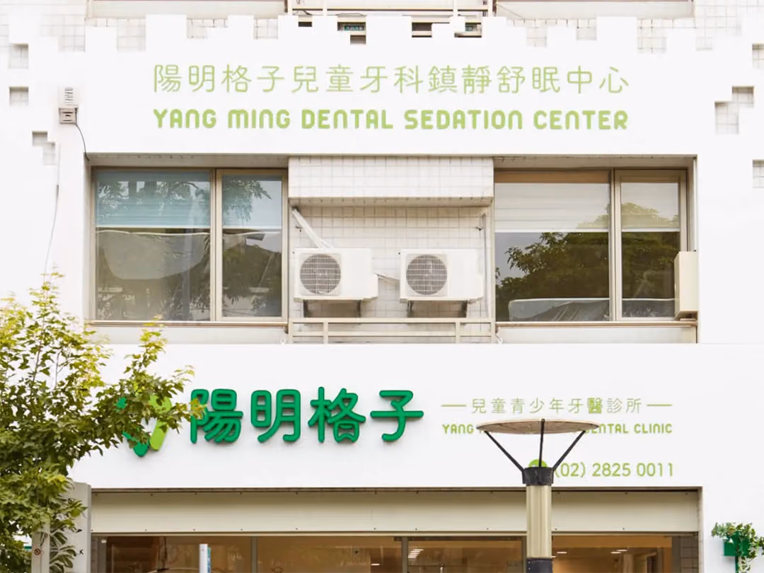 日間白色外牆,上段淺綠平面字,下段深綠立體字,兩段皆未點亮,二樓窗台放冷氣機,一樓玻璃門面